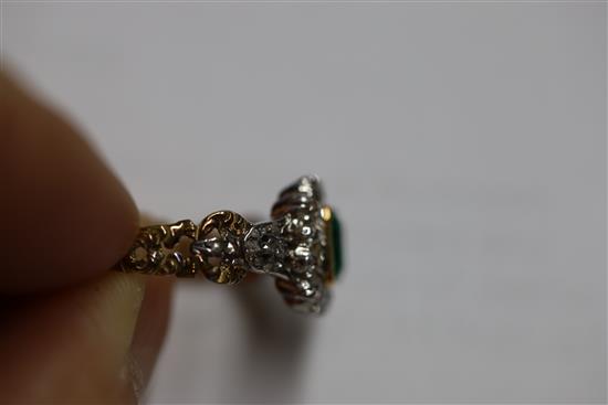 An antique 18ct gold, emerald and diamond cluster ring, the central square cut emerald (0.88ct) bordered by 14 old cut diamonds,